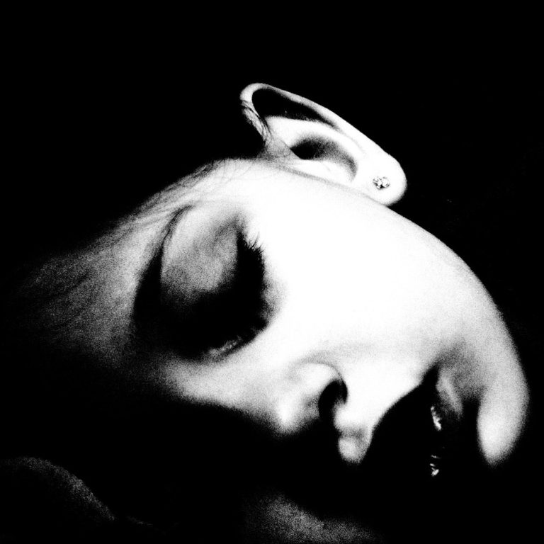 Schlafendes Kind mit geschlossenem Auge auf schwarzem Hintergrund.