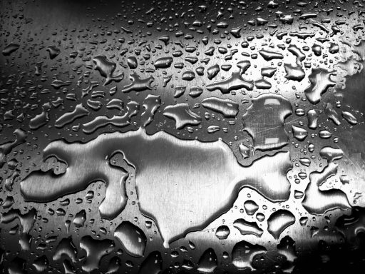Wassertropfen auf einer glatten, reflektierenden Oberfläche.