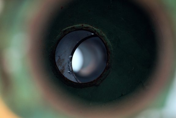 Blick durch ein zylindrisches Objekt mit schwachem Licht am Ende. Es erinnert an eine menschliche Pupille.