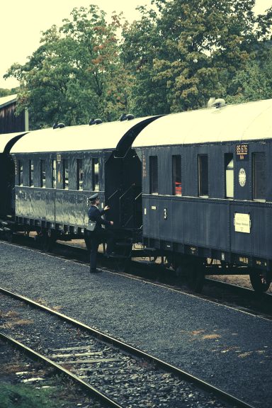 Ein Zug mit historischen Waggons auf einem Gleis, ein Mann steht daneben.